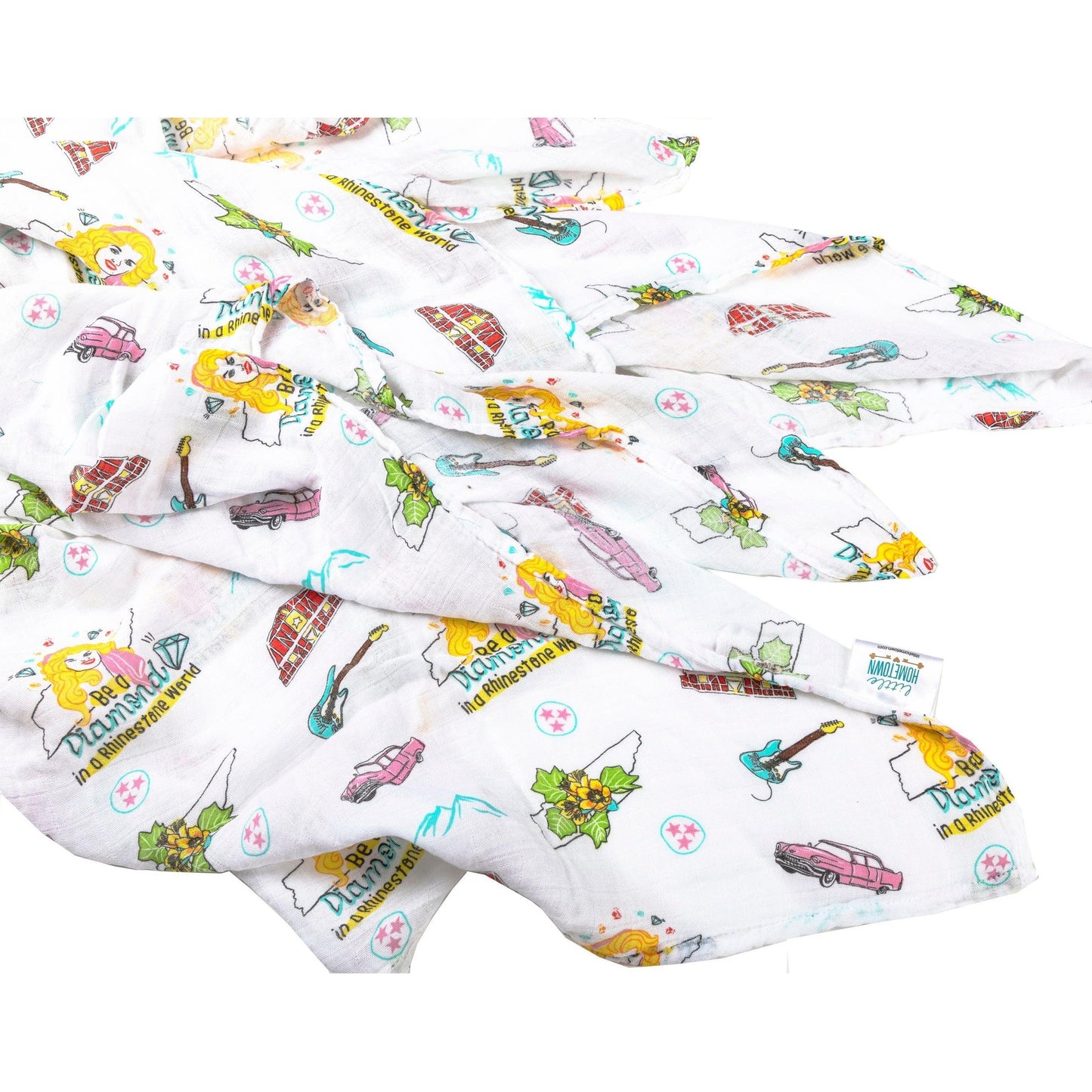 The Tennessee Floral muslin swaddle blanket rippling across white with guitars, boats and hot chicken.