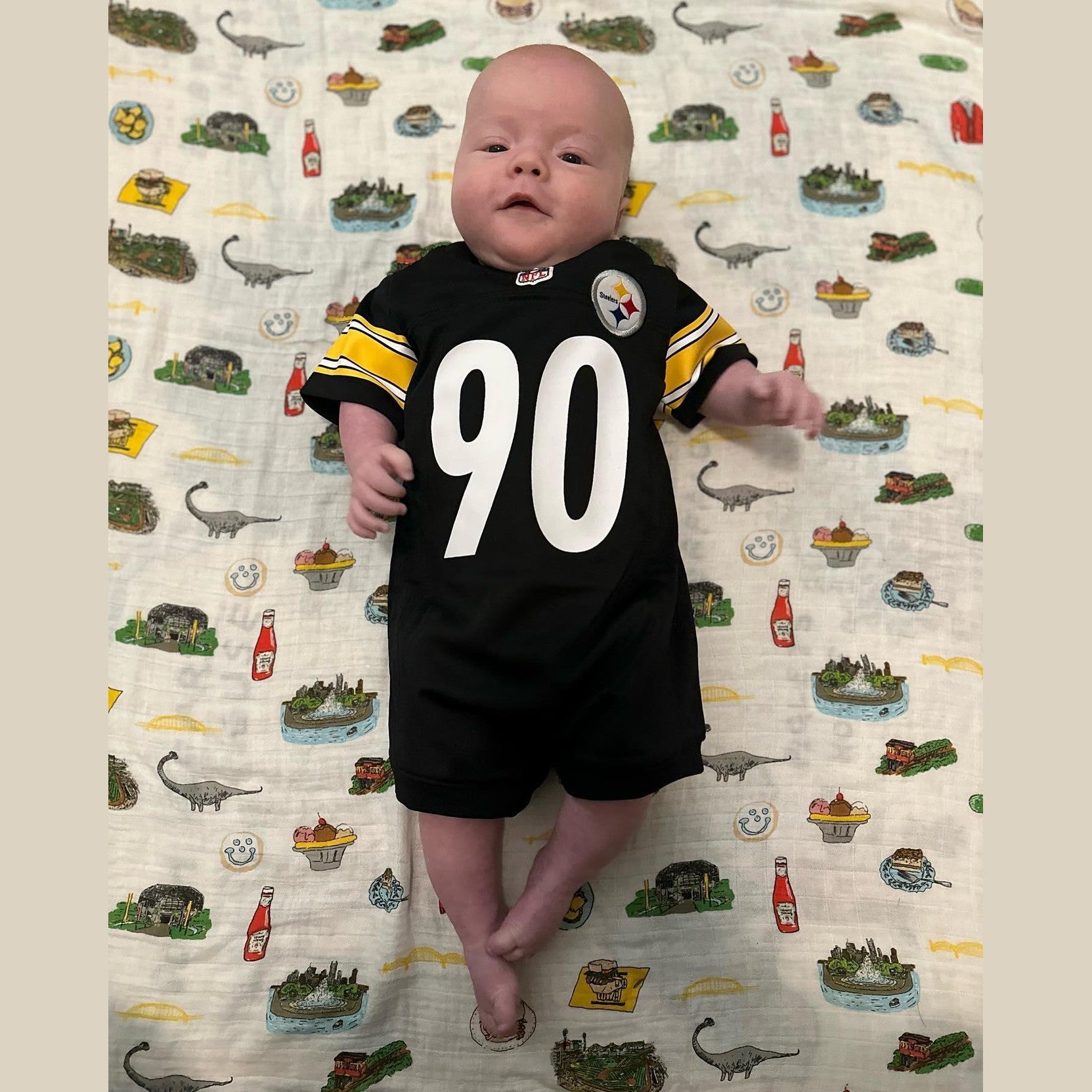 Pittsburgh-themed baby gift set with muslin swaddle blanket, burp cloth, and bib featuring city landmarks.