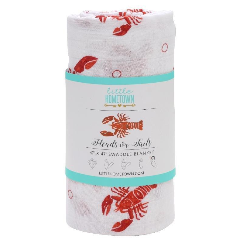The Heads or Tails muslin swaddle blanket rolled and banded, bright red lobsters scattered across it.