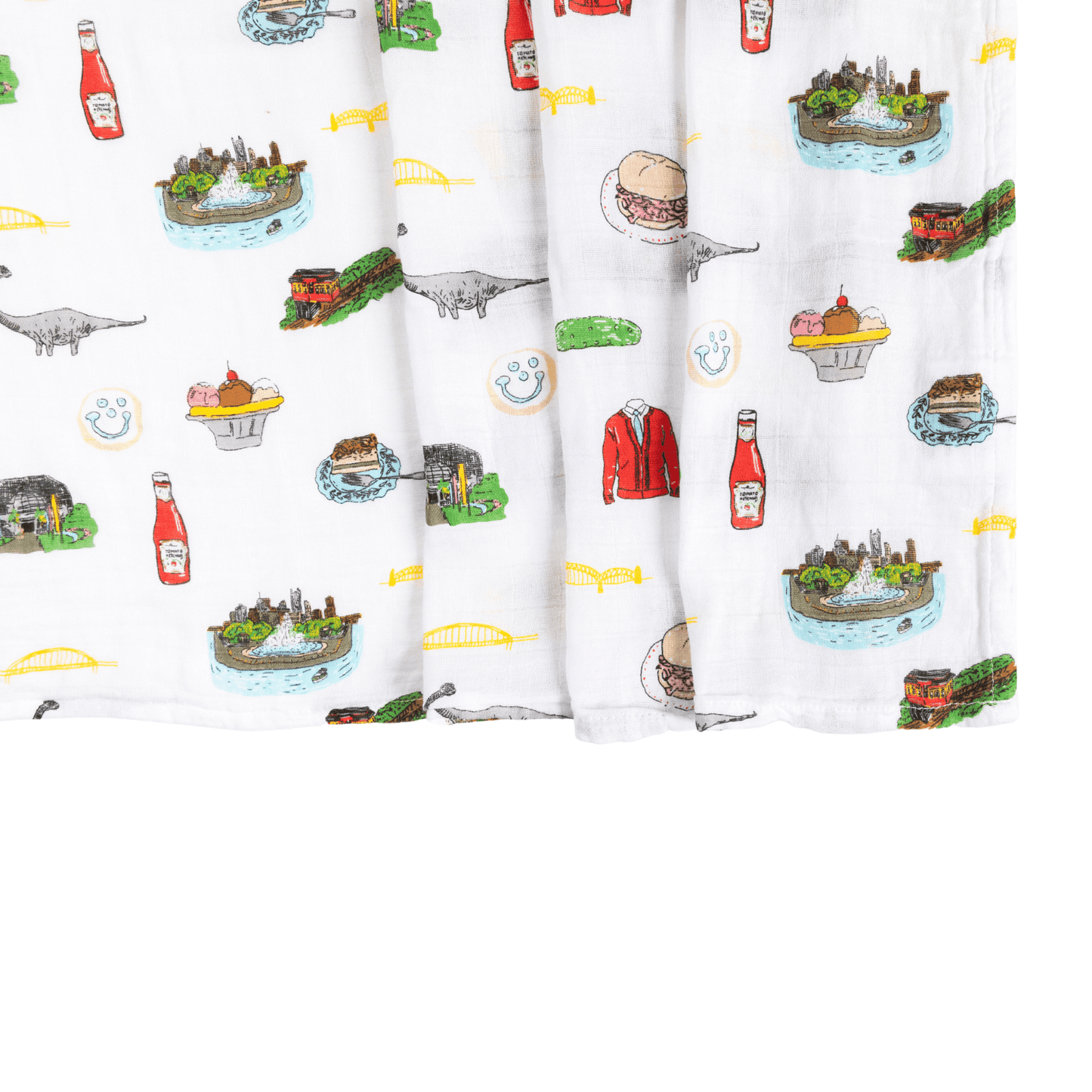 The Pittsburgh muslin swaddle blanket, folded to show ketchup bottles, sandwiches and a friendly dinosaur.