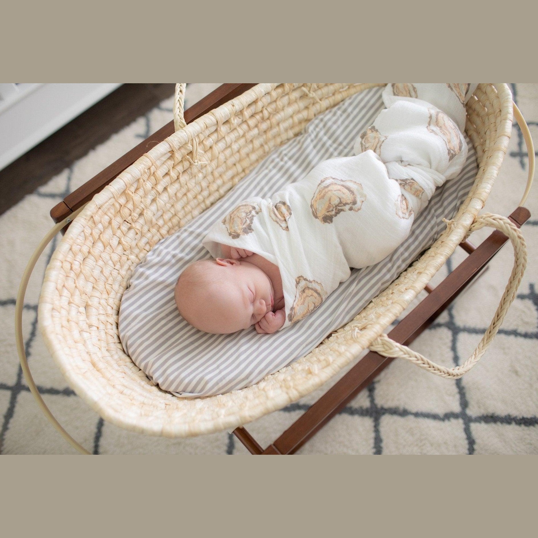 White muslin swaddle blanket with playful oyster illustrations and the text "Aw Shucks!" in blue script.