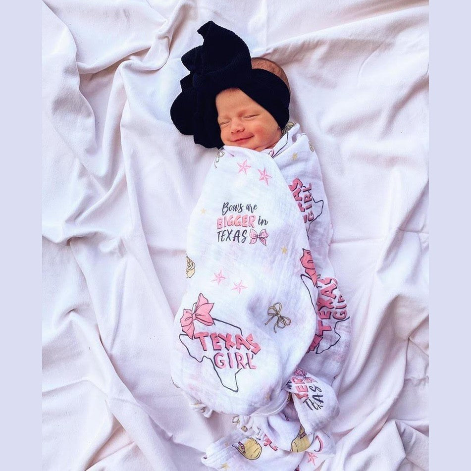 Texas-themed baby girl gift set with a muslin swaddle blanket and burp cloth, featuring pink and white designs.