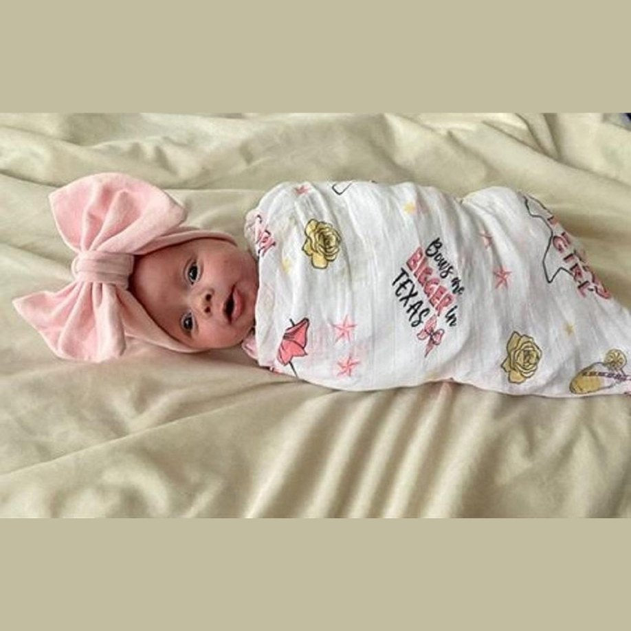 Texas-themed baby girl gift set with a muslin swaddle blanket and burp cloth/bib combo, featuring pink and white designs.