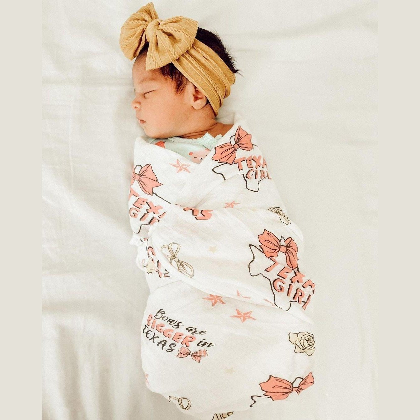 Texas-themed baby girl gift set with a muslin swaddle blanket and burp cloth, featuring pink and white designs.