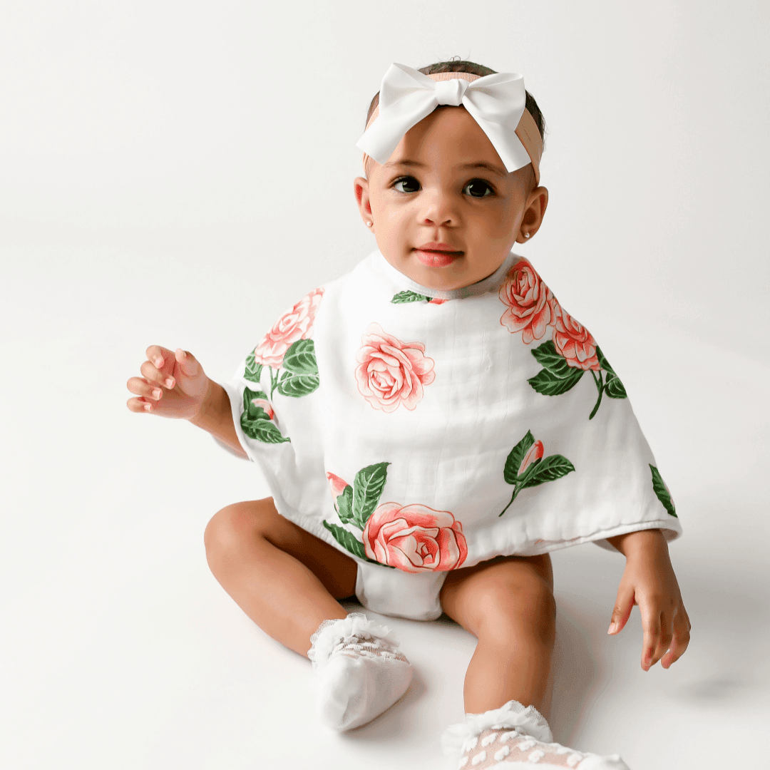 Gift set with a floral muslin swaddle blanket and matching burp cloth, featuring pink camellia flowers.