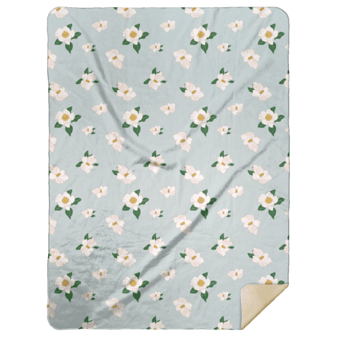 The Magnolia plush throw blanket folded neatly on a deep green backdrop, white blooms across it.