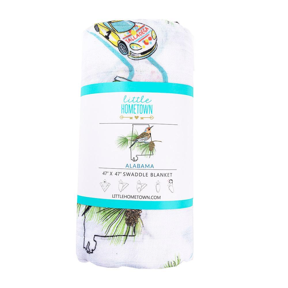 The Alabama muslin swaddle blanket, rolled and wrapped in its printed Little Hometown band.