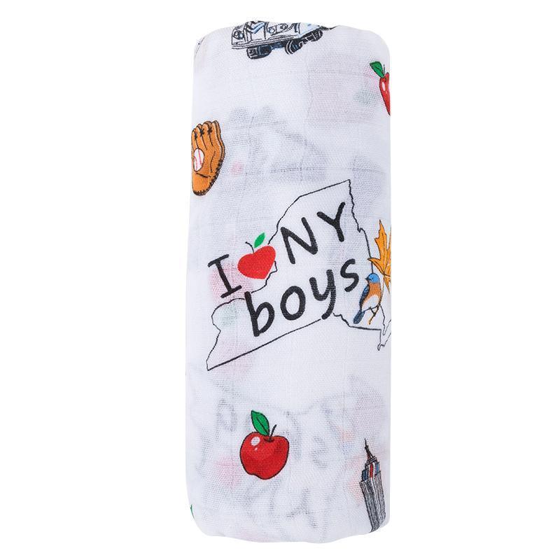 The New York muslin swaddle blanket for boys, rolled up with apples and taxis peeking through.