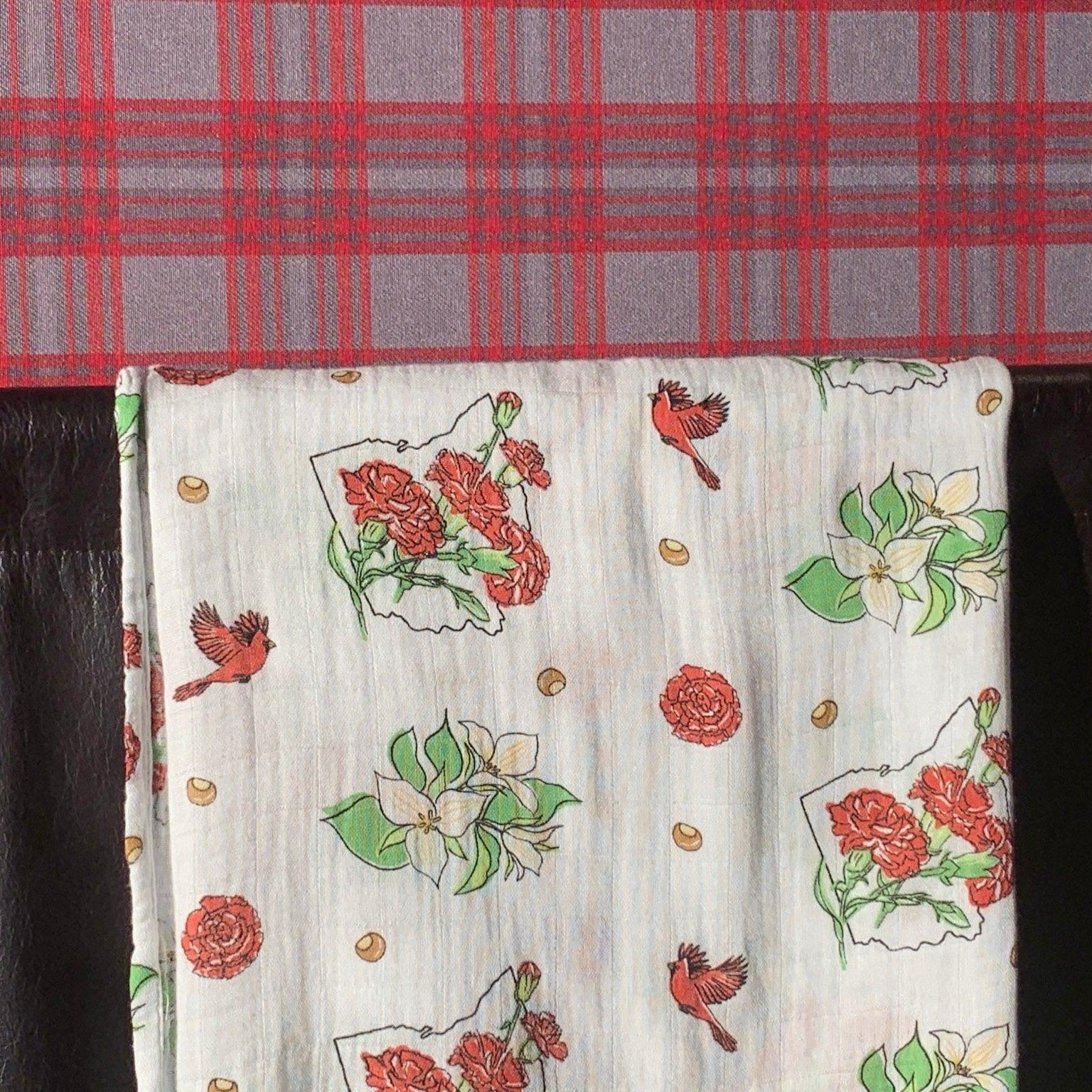 Soft muslin swaddle blanket with delicate floral pattern, featuring pink and green flowers on a white background.