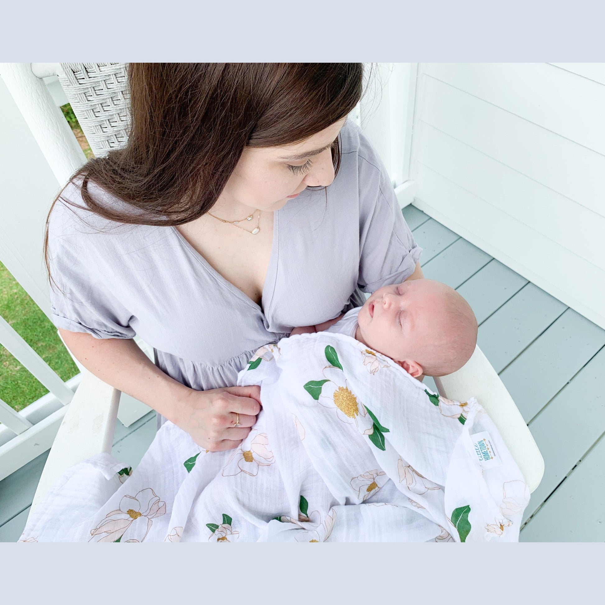 Soft muslin swaddle blanket with delicate Southern Magnolia print, featuring white flowers and green leaves.