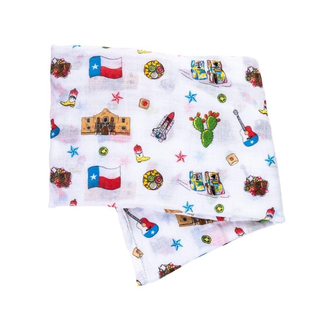 Texas-themed baby muslin swaddle blanket with state icons like cowboy boots, armadillos, and bluebonnets.
