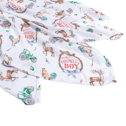 Country Boy muslin swaddle blanket with a playful farm animal print, featuring cows, pigs, and tractors.