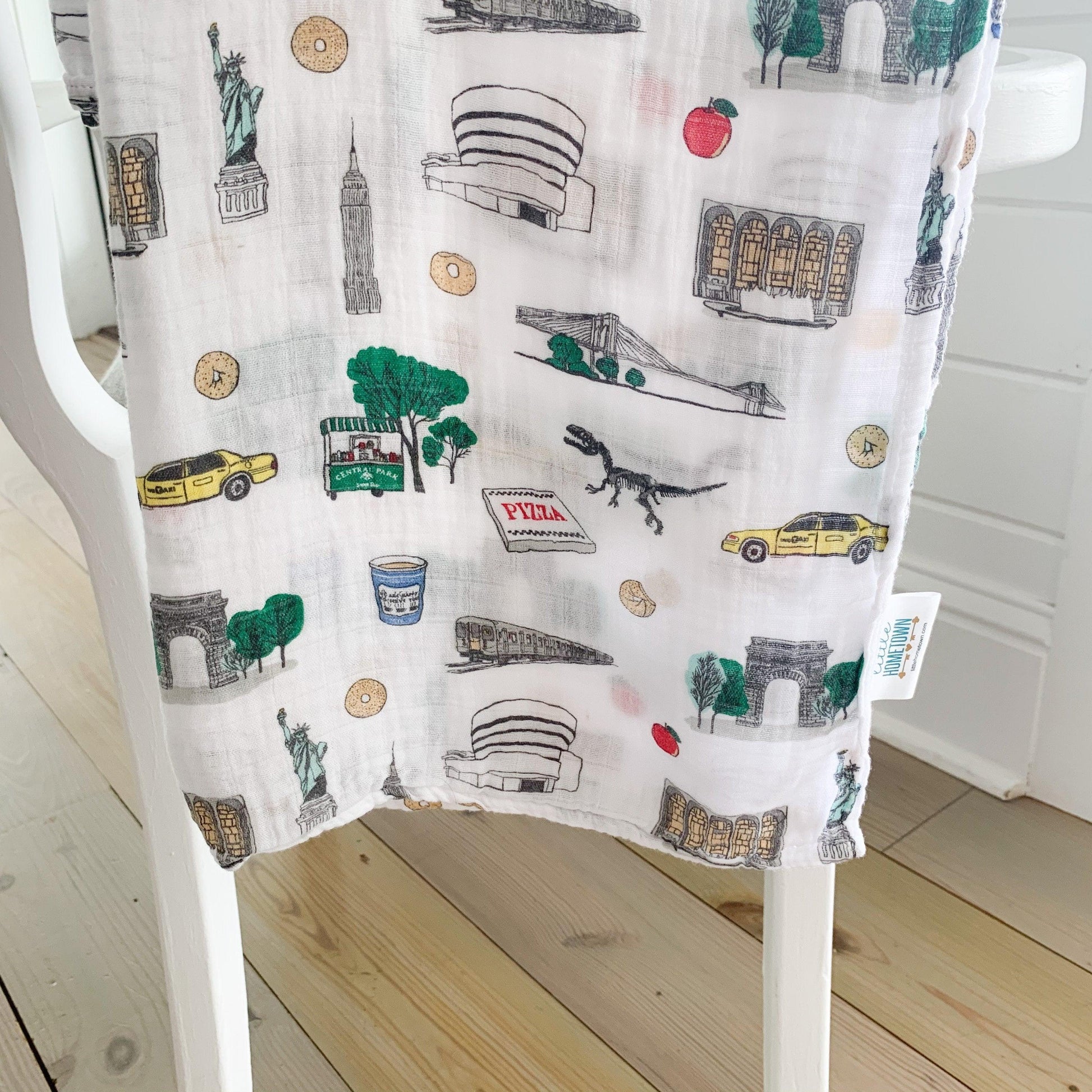 New York City-themed baby muslin swaddle blanket with iconic landmarks in soft pastel colors.