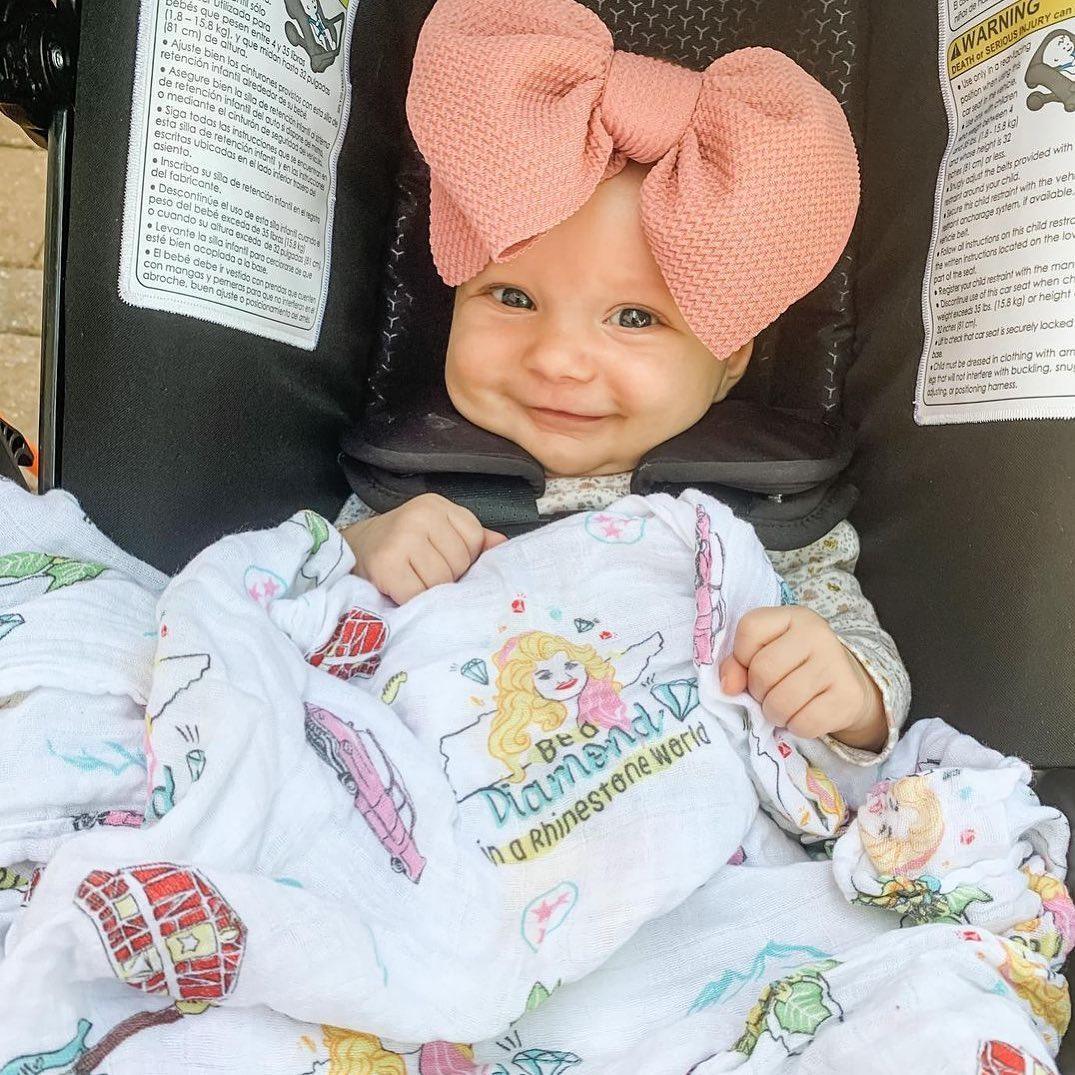 Tennessee-themed baby muslin swaddle with floral design, featuring state symbols and landmarks in soft pastel colors.