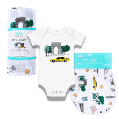 The Washington Square Park muslin swaddle blanket laid out with its one piece, bib and gift box.