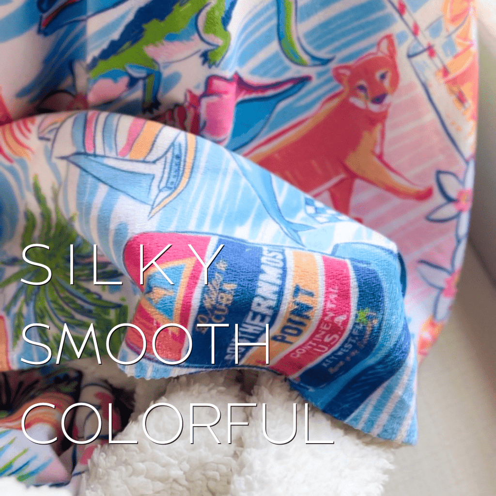 A picture of a Southern Florida themed plush blanket in vibrant pinks, blues, and yellows measuring 60x80 inches with the words Silky, Smooth, Colorful written in white letters