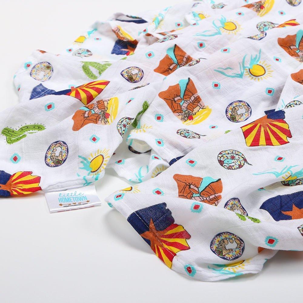 Soft muslin swaddle blanket with Arizona-themed illustrations, including cacti, mountains, and desert animals.