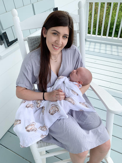 White muslin swaddle blanket with cute oyster illustrations and the text "Aw Shucks!" in playful blue font.