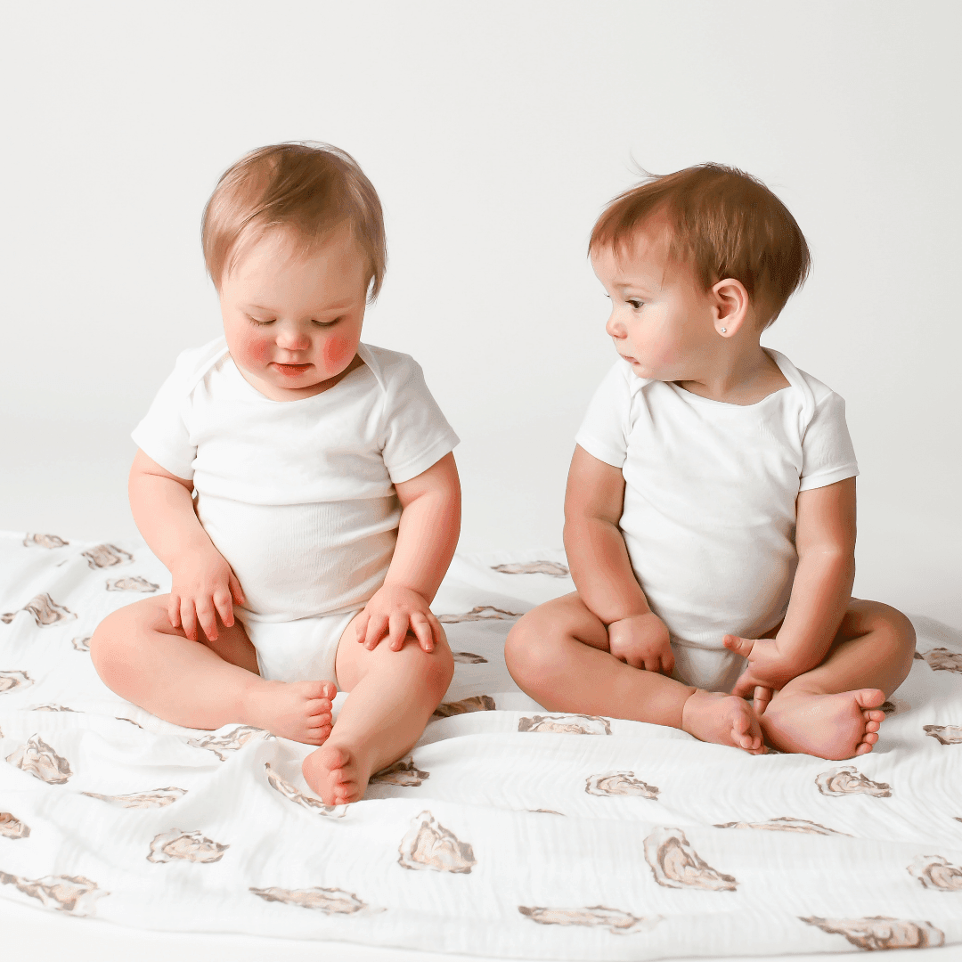 White muslin swaddle blanket with cute oyster illustrations and the text "Aw Shucks!" in playful font.
