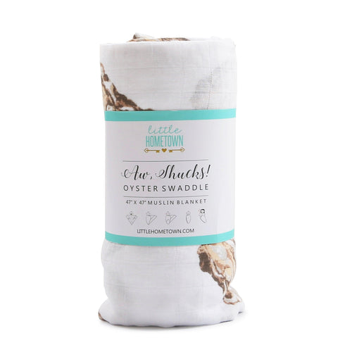 White muslin swaddle blanket with playful oyster illustrations and the text 