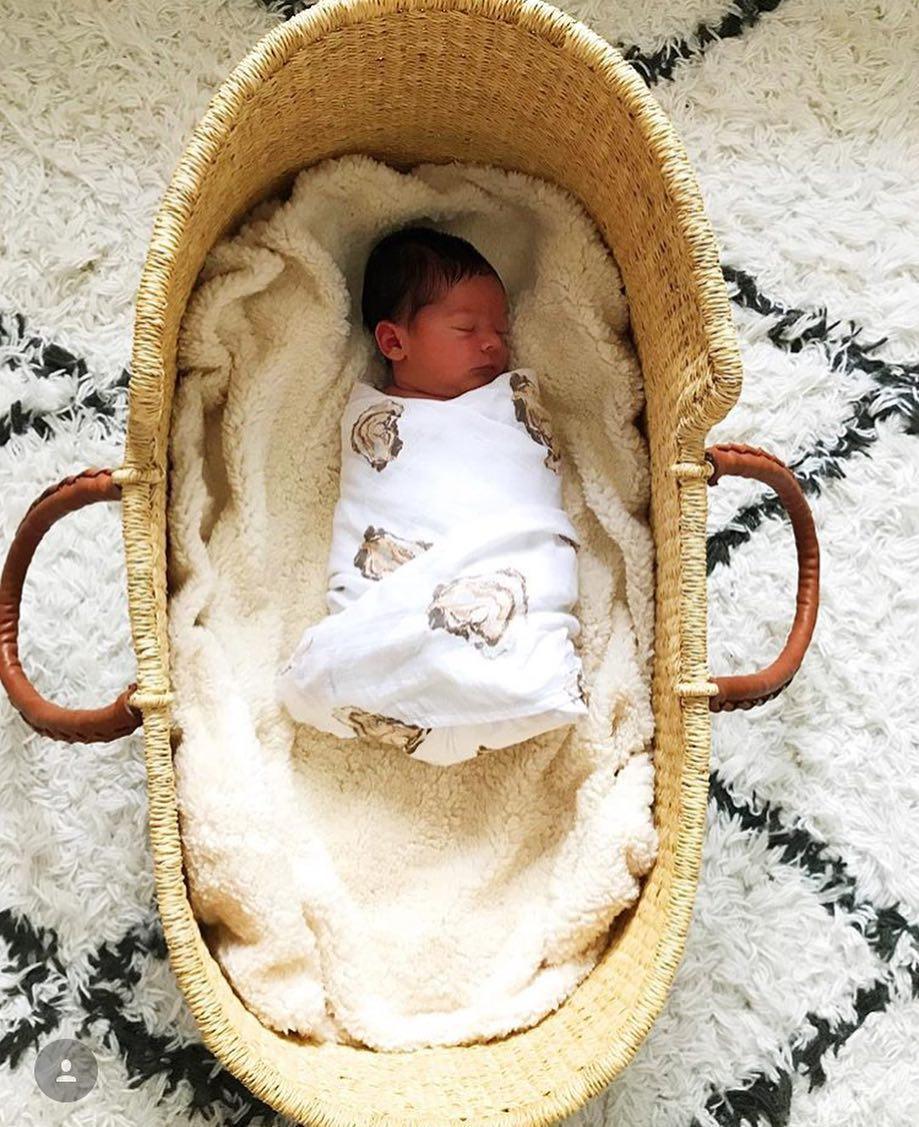 White muslin swaddle blanket with playful oyster illustrations and the text "Aw Shucks!" in blue script.