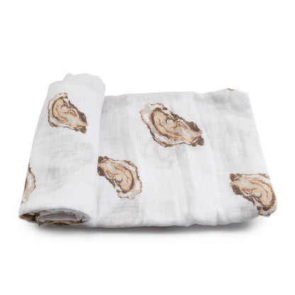 White muslin swaddle blanket with playful oyster illustrations and the text "Aw Shucks!" in blue script.