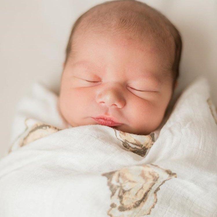 White muslin swaddle blanket with playful oyster illustrations and the text "Aw Shucks!" in blue script.