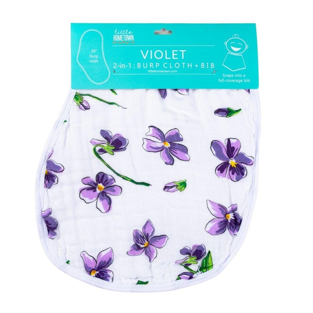Soft violet baby bib and burp cloth set with white floral patterns, neatly displayed on a white background.
