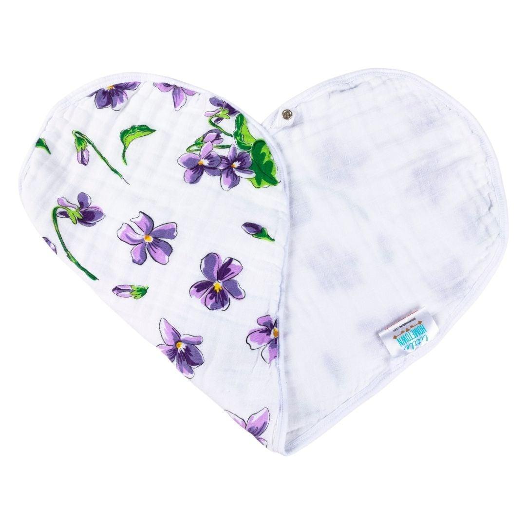 Violet baby bib and burp cloth set with white floral patterns, neatly arranged on a white background.