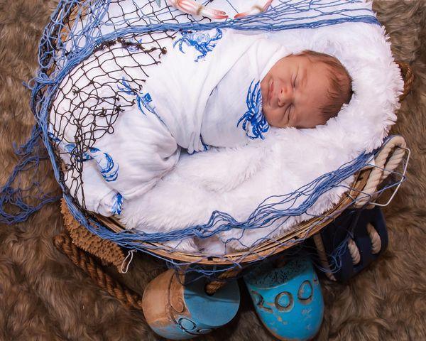 White muslin swaddle blanket with blue crab illustrations, folded neatly on a white background.