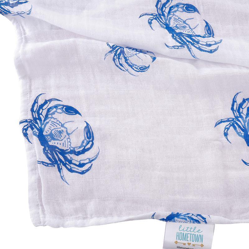 White muslin swaddle blanket with blue crab illustrations, folded neatly on a white background.