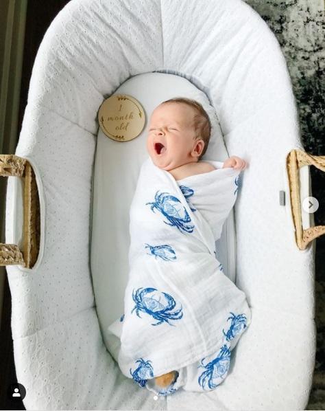 White muslin swaddle blanket with blue crab illustrations, folded neatly on a white background.