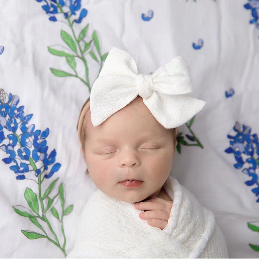 White muslin swaddle blanket adorned with delicate bluebonnet flowers, evoking a serene and gentle ambiance.