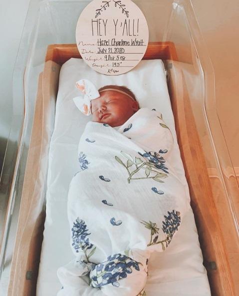 White muslin swaddle blanket with bluebonnet flower pattern, neatly folded on a white background.