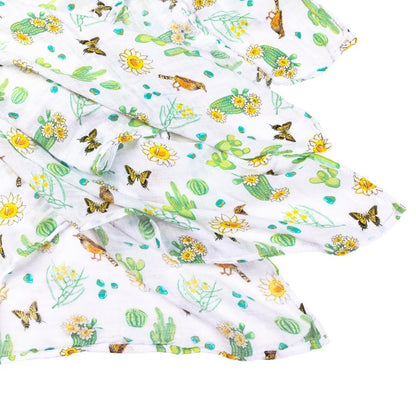 Soft muslin swaddle blanket with a vibrant cactus blossom print, featuring pink flowers and green cacti.