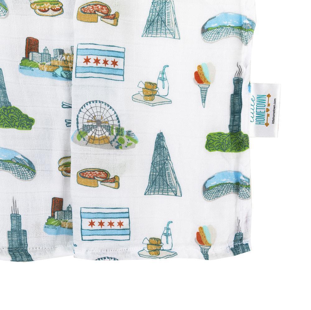 White muslin swaddle blanket with Chicago landmarks like the Willis Tower, Navy Pier, and the Bean in colorful illustrations.