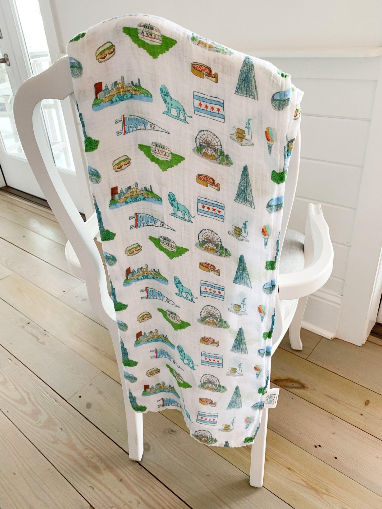 White muslin swaddle blanket with Chicago landmarks like the Willis Tower, Navy Pier, and the Bean in colorful illustrations.