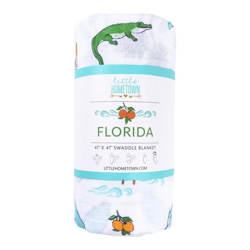 White muslin swaddle blanket with colorful Florida-themed illustrations, including oranges, flamingos, and palm trees.