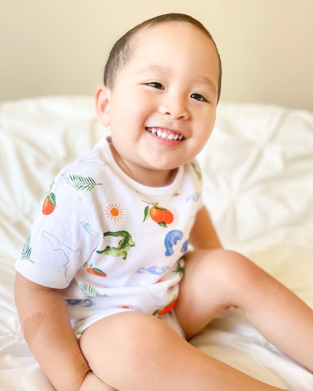 Toddler wearing Florida-themed pajamas with colorful state icons, standing on a white background.