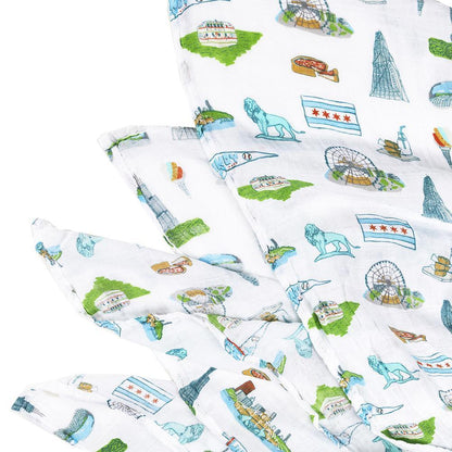 Chicago-themed baby gift set with muslin swaddle blanket, burp cloth, and bib featuring city landmarks.