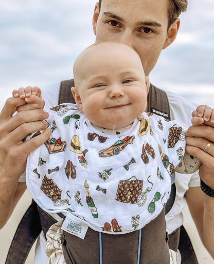 Baby gift set with a muslin swaddle blanket and burp cloth featuring a dapper napper design in soft pastel colors.