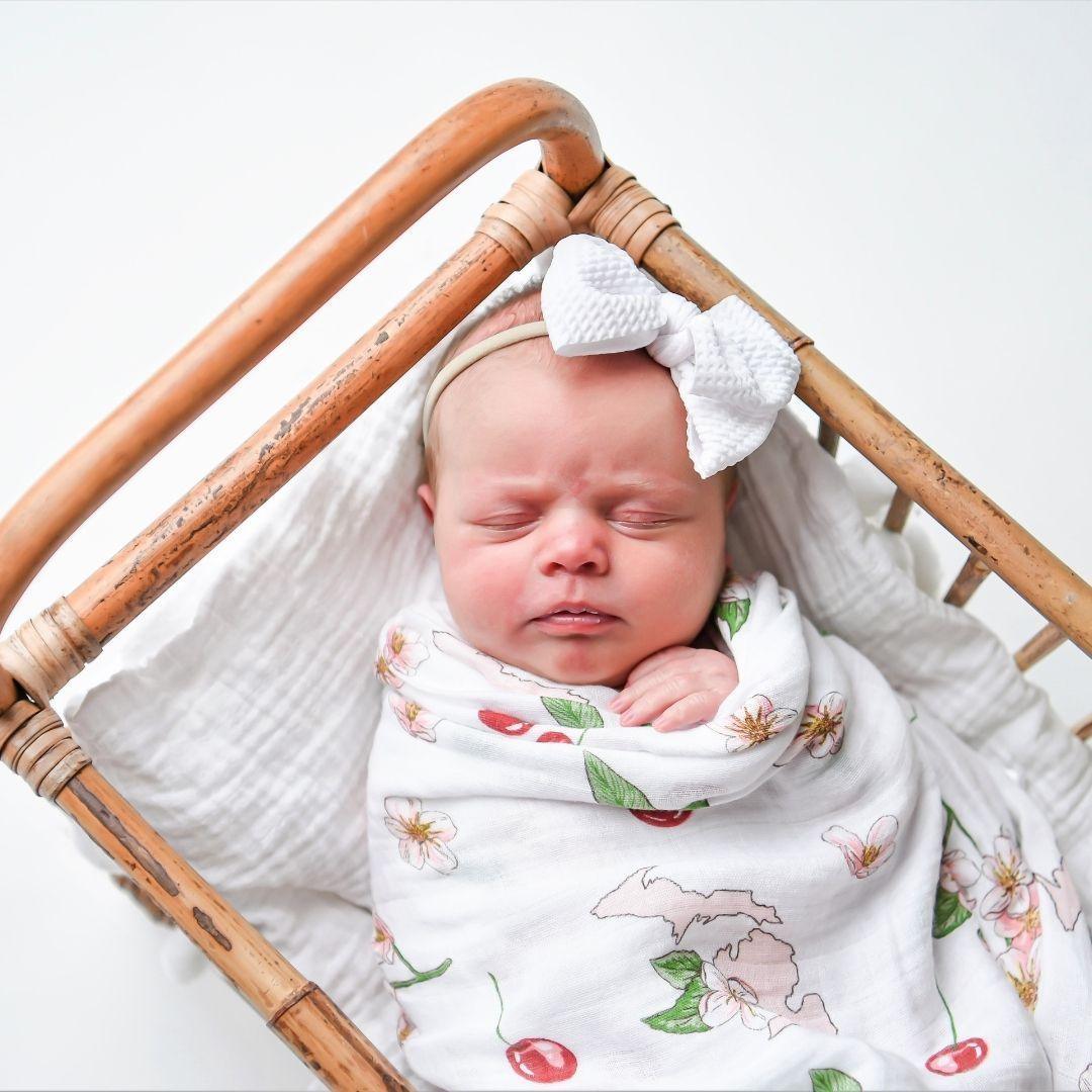 Michigan-themed baby gift set with floral muslin swaddle blanket and matching burp cloth/bib combo on white background.