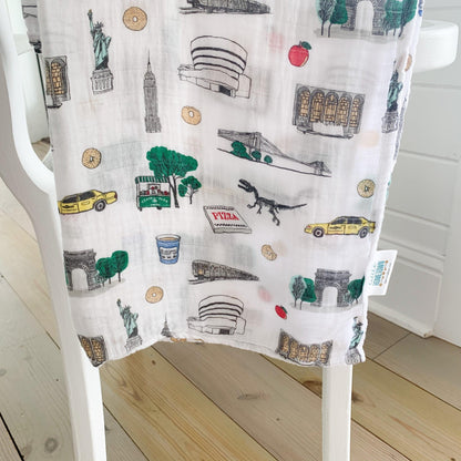 New York City-themed baby gift set with muslin swaddle blanket and burp cloth, featuring iconic landmarks.