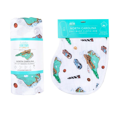 The North Carolina burp cloth and bib combo laid beside its matching rolled swaddle in the gift set.