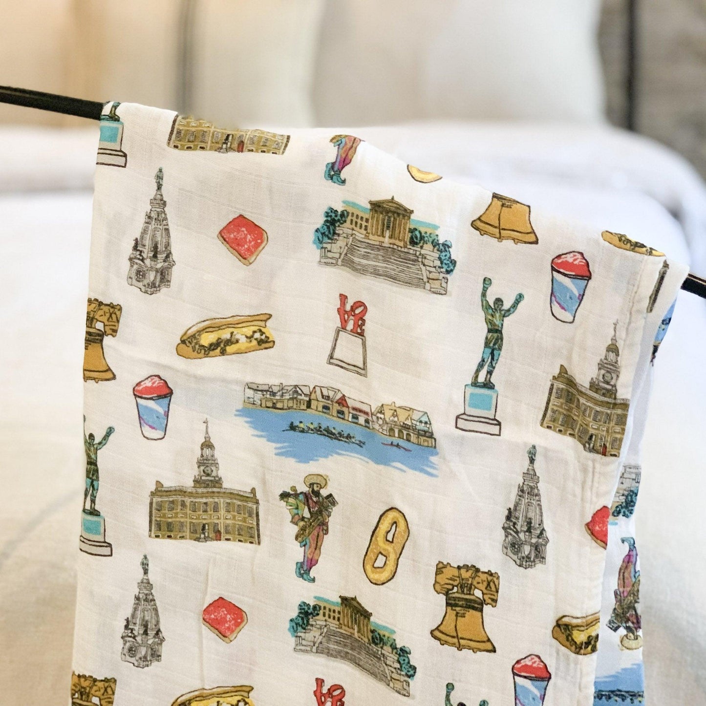 Philadelphia-themed baby muslin swaddle blanket and burp cloth set, featuring iconic city landmarks in soft pastel colors.