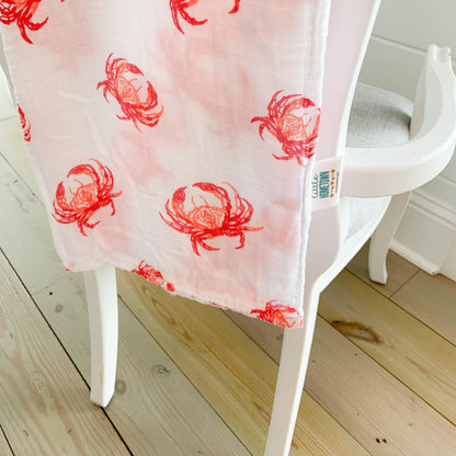 Pink crab-themed baby muslin swaddle blanket and burp cloth set, neatly folded on a white background.