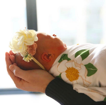 Southern Magnolia baby muslin swaddle blanket and burp cloth set with delicate floral design on soft fabric.