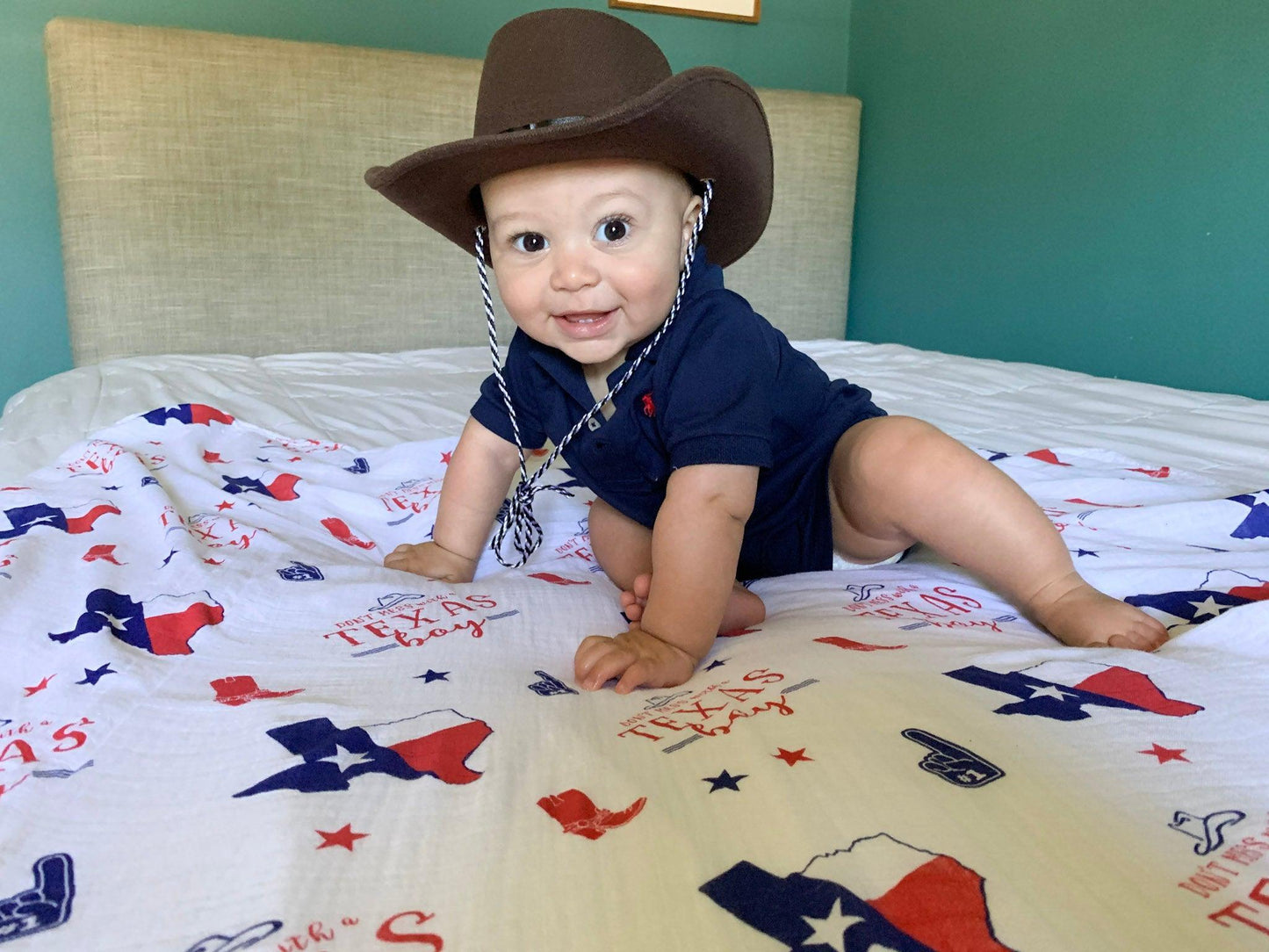 Texas-themed baby gift set with muslin swaddle blanket, burp cloth, and bib featuring state icons and blue accents.