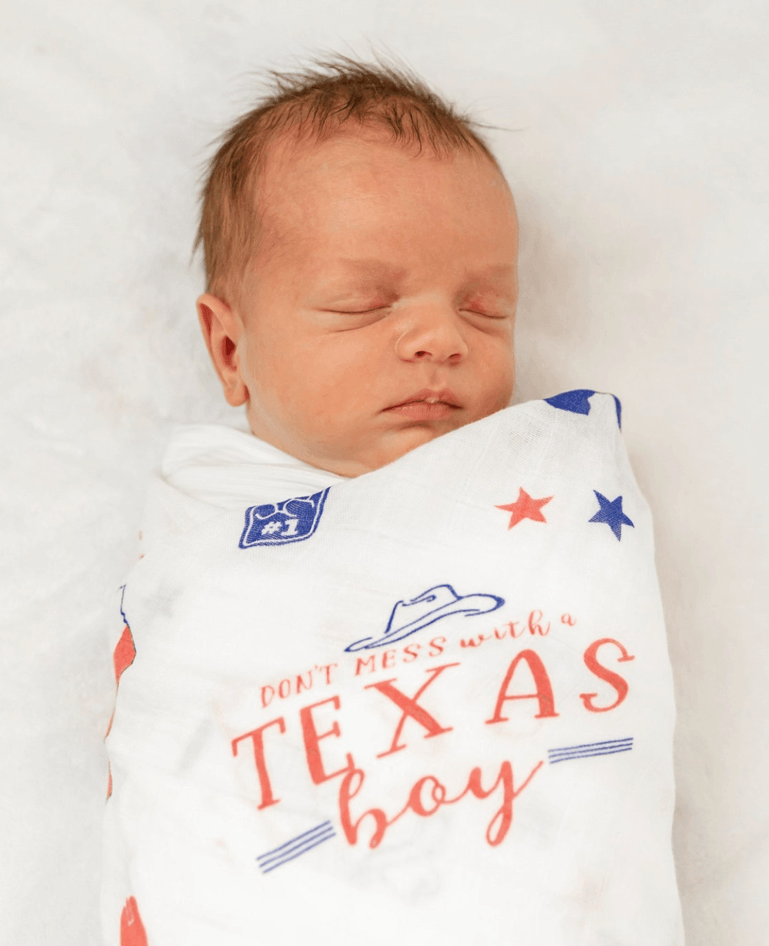 Texas-themed baby gift set with a muslin swaddle blanket and burp cloth, featuring blue and white designs.