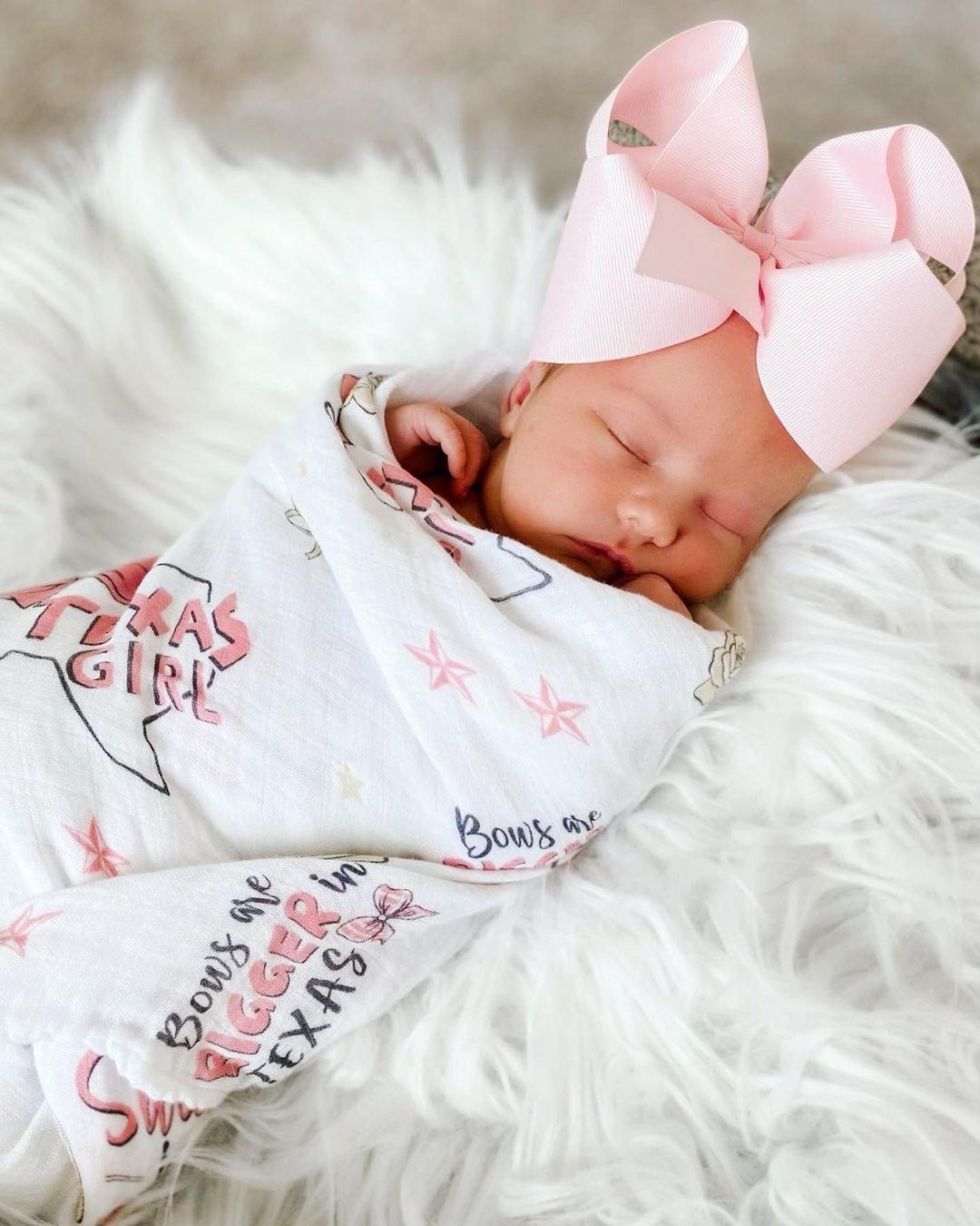 Texas-themed baby girl gift set with a muslin swaddle blanket and burp cloth, featuring pink and white designs.